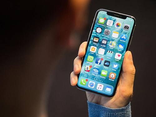 Ein Mann hält ein iPhone X in der Hand. 