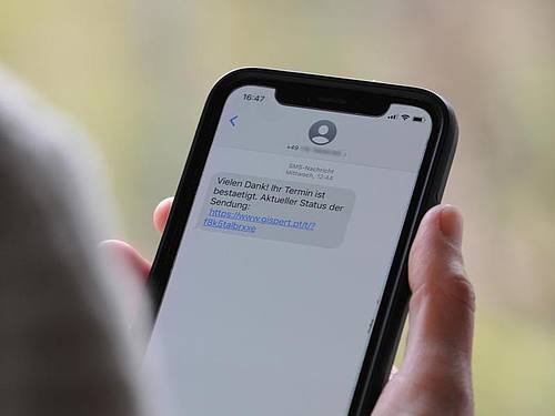 Eine Frau hält ein Smartphone in ihrer Hand, auf dessen Display eine Betrugs-SMS zu lesen ist. Foto: Wolf von Dewitz/dpa