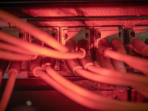 Glasfaserkabel führen zu einem Internet Switch in einem Serverraum. Foto: Michael Kappeler/dpa
