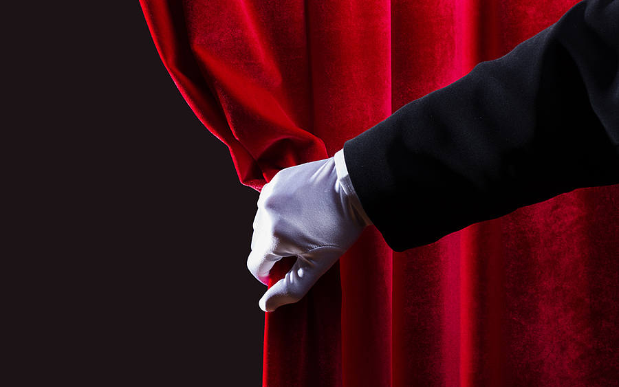 Hand schiebt Theatervorhang zur Seite