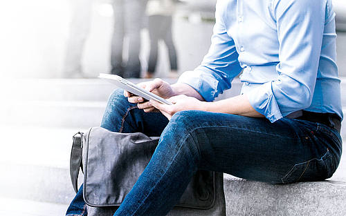 Mann sitzt mit Tablet auf Treppe