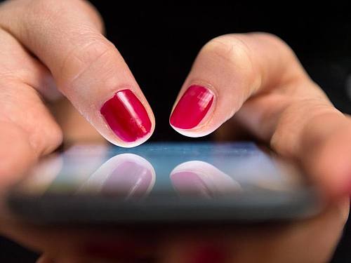 Eine Frau tippt auf einem Smartphone. Foto: Sebastian Gollnow/Illustration