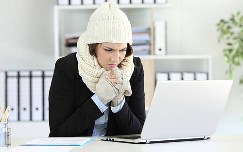 Frau sitzt mit Mütze am Schreibtisch