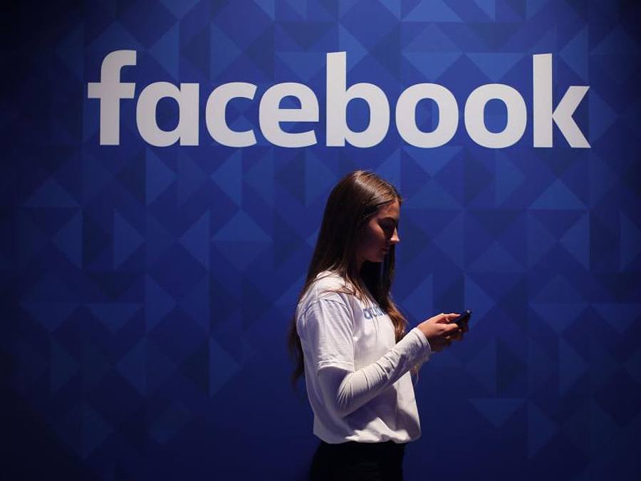 Eine Frau steht mit ihrem Smartphone unter dem Facebook-Schriftzug. Foto: Niall Carson/PA Wire/dpa