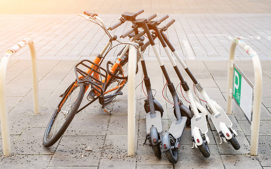 E-Tretroller lehnen an einem Fahrradständer