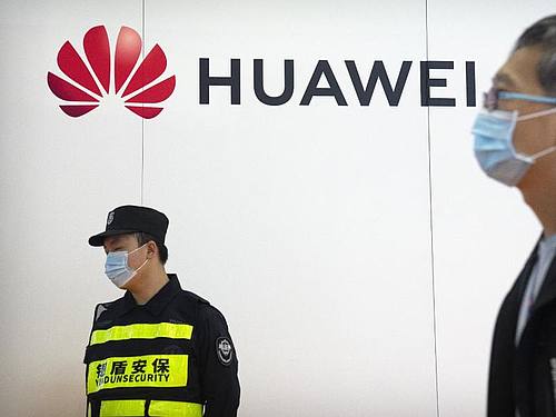 Ein Wachmann steht auf der PT Expo in Peking an einem Stand des chinesischen Technologieunternehmens Huawei. Foto: Mark Schiefelbein/AP/dpa