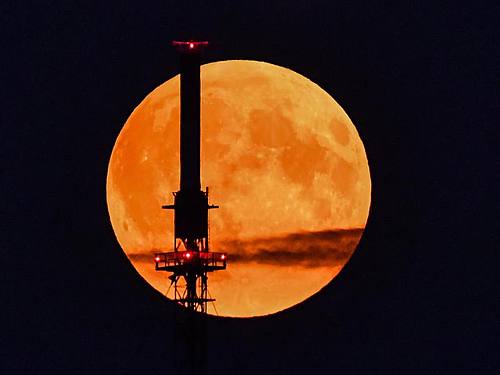 Der rötlich schimmernde Vollmond leuchtet hinter einem Funkmast. Foto: Patrick Pleul/dpa-Zentralbild/dpa