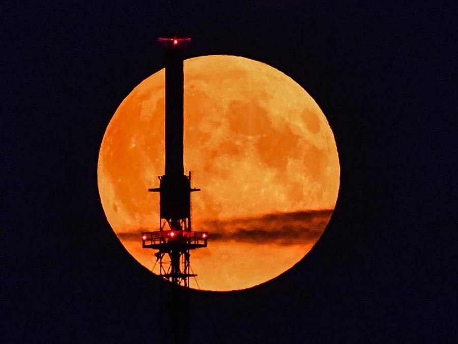 Der rötlich schimmernde Vollmond leuchtet hinter einem Funkmast. Foto: Patrick Pleul/dpa-Zentralbild/dpa