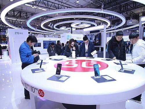 Besucher schauen in Peking neue Smartphones mit 5G-Technologie an. Foto: Chen Xiaogen/SIPA Asia via ZUMA Wire/dpa