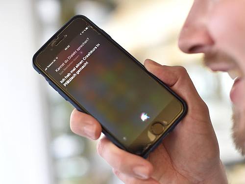 Ein Mann gibt einem Sprachassistenten auf seinem Smartphone einen Befehl