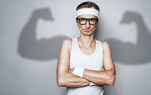 Nerd mit Strinband ohne Muskeln mit Muskleschatten