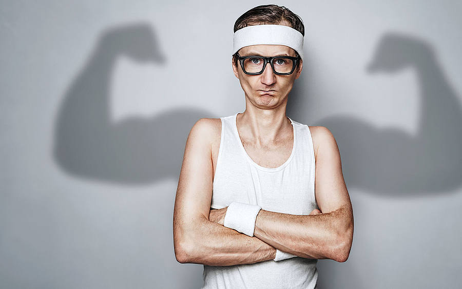 Nerd mit Strinband ohne Muskeln mit Muskleschatten