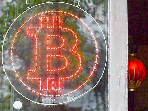 Ein Bitcoin-Logo in einem Schaufenster einer Kneipe im Kreuzberger Graefekiez. Foto: Jens Kalaene/ZB/dpa