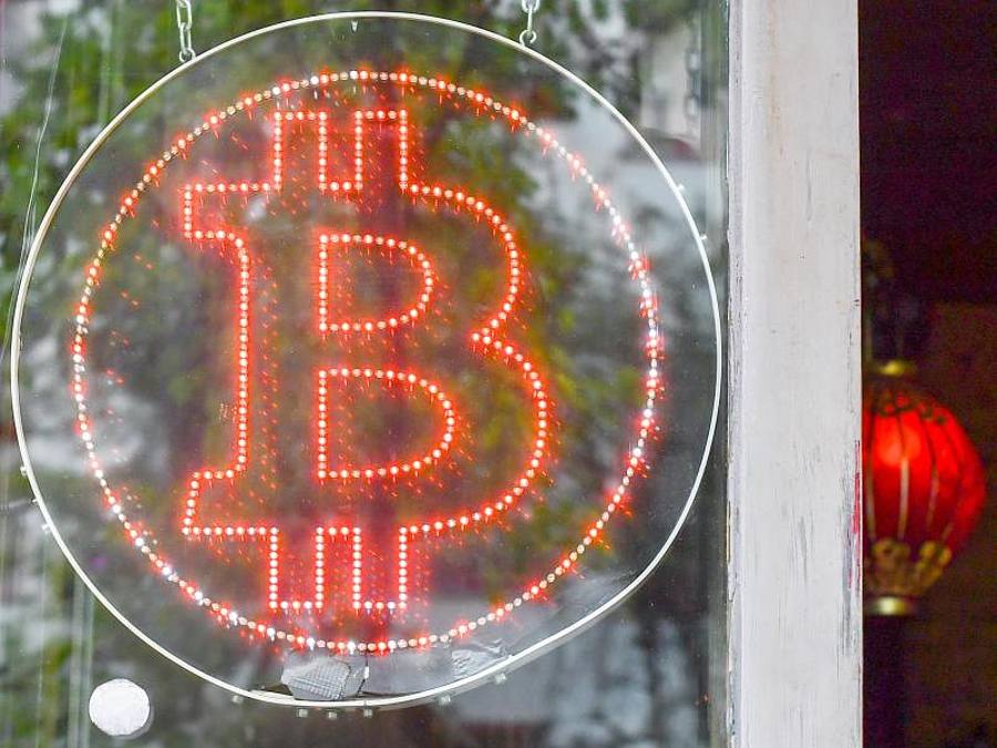 Ein Bitcoin-Logo in einem Schaufenster einer Kneipe im Kreuzberger Graefekiez. Foto: Jens Kalaene/ZB/dpa