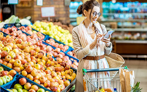 Frau mit Smartphone im Supermarkt