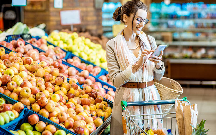Frau mit Smartphone im Supermarkt