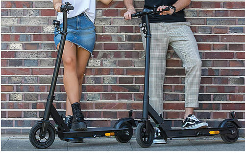 Zwei junge Menschen mit E-Rollern.