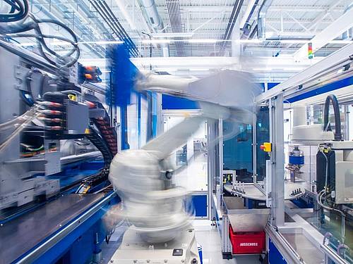 Ein Industrieroboter nimmt unter Reinraumbedingungen einen Halter für Insulinspritzen in einer Produktionshalle eines neu errichteteten Werks des Schweizer Medizintechnikunternehmens Ypsomed aus einer Maschine. Foto: Jens Büttner/dpa-Zentralbild/dpa