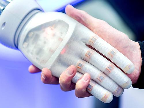 Ein Mann hält am Stand des Unternehmens Festo auf der Hannover Messe die Hand eines bionischen Roboters. Internet der Dinge, 5G, künstliche Intelligenz und Big Data: Technologie wälzt in der vierten industriellen Revolution die Wirtschaft um. Foto: Hau