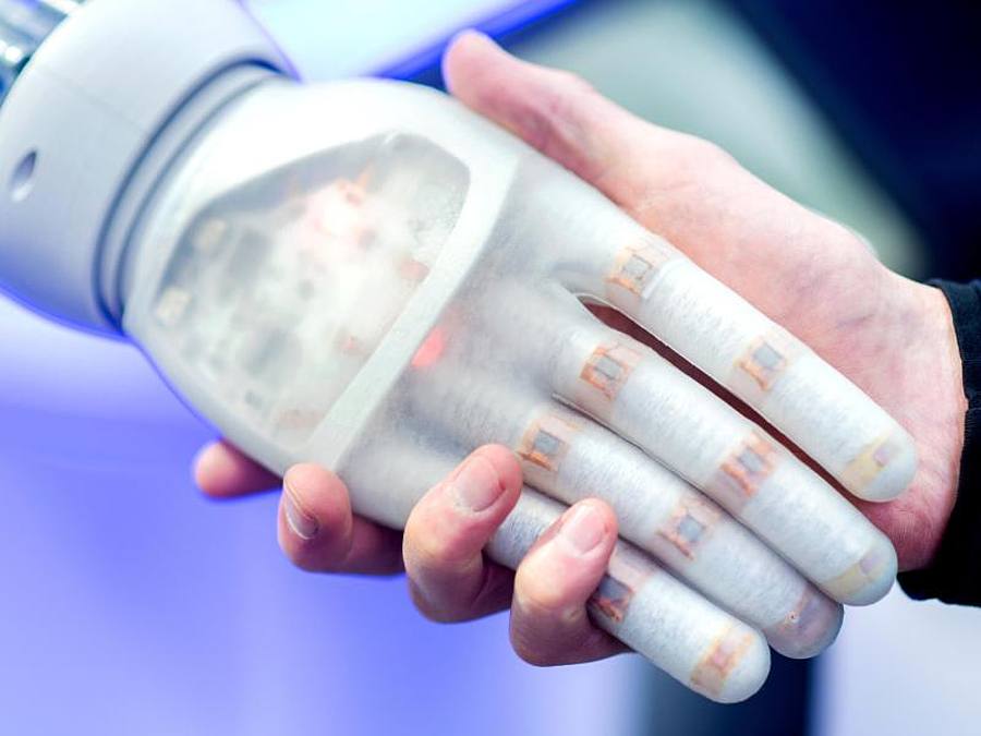 Ein Mann hält am Stand des Unternehmens Festo auf der Hannover Messe die Hand eines bionischen Roboters. Internet der Dinge, 5G, künstliche Intelligenz und Big Data: Technologie wälzt in der vierten industriellen Revolution die Wirtschaft um. Foto: Hau