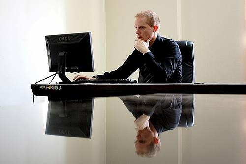 Geschäftsmann am Schreibtisch schaut auf Computer