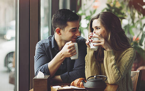 Junges Paar sitzt flirtend im Café