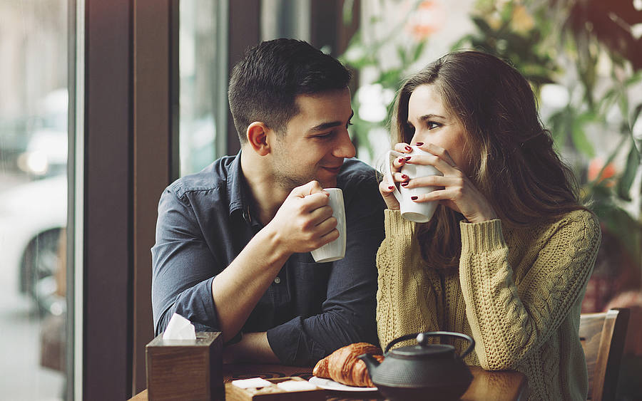 Junges Paar sitzt flirtend im Café