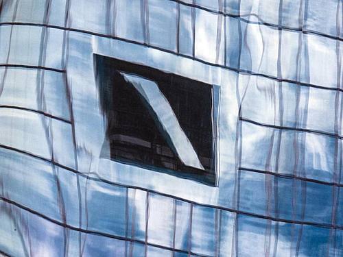 Die Zentrale der Deutschen Bank in Frankfurt am Main spiegelt sich in einer Glasfassade. Foto: Boris Roessler/dpa