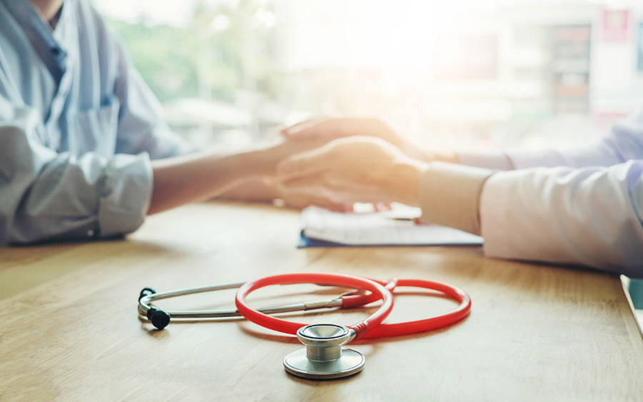 Arzt und Patient halten sich an den Händen