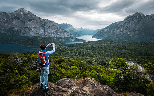 Ein Rucksack-Tourist fotografiert ein Bergpanorama mit dem Smartphone