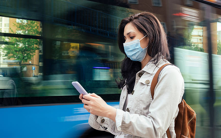 Frau mit Handy vor Bus