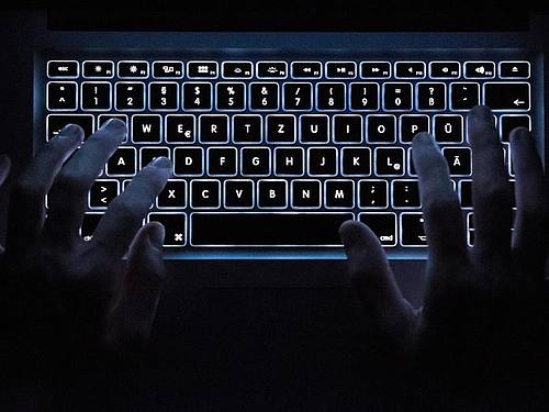 Ein Mann benutzt die beleuchtete Tastatur eines Notebooks. Foto: Silas Stein/dpa/Symbolbild