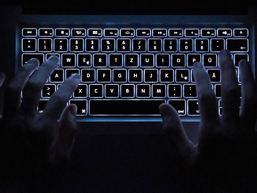 Ein Mann benutzt die beleuchtete Tastatur eines Notebooks. Foto: Silas Stein/dpa/Symbolbild