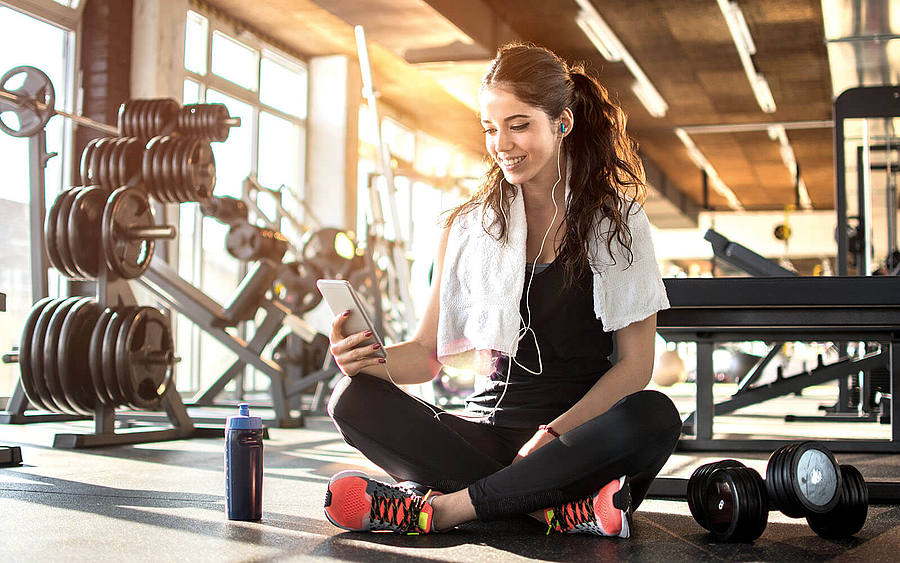Frau mit Smartphone im Fitnessstudio
