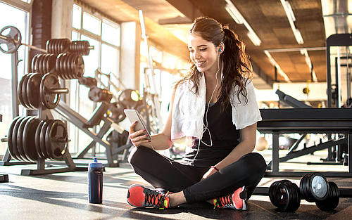 Frau mit Smartphone im Fitnessstudio
