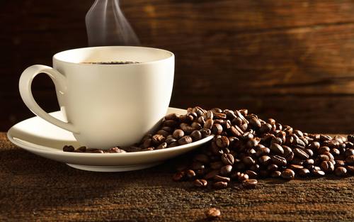 Eine Tasse Kaffee mit Bohnen daneben
