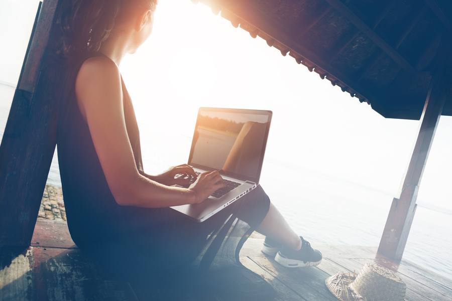 Freiberuflerin arbeitet mit Laptop am Strand
