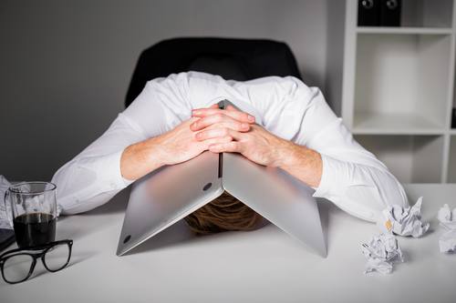 Mann versteckt Kopf unter notebook