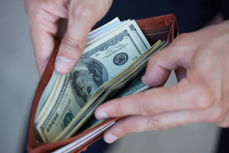 Hände öffnen Geldbörse mit Dollarscheinen