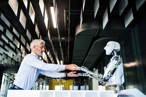 Roboter und Mensch geben sich die Hände