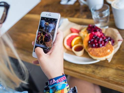 So schmeckt es manchen noch besser: Eine junge Frau fotografiert mit einem Smartphone ihr Essen. Foto: Sophia Kembowski