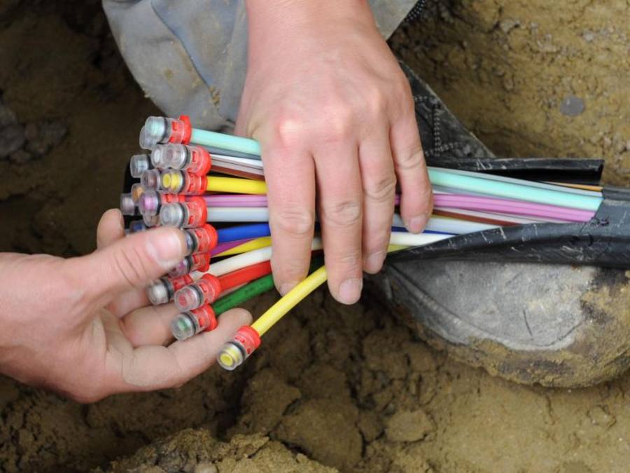 Ein Mann fächert in München (Bayern) ein Glasfaser-Kabel mit farbigen Einzelsträngen auseinander. Der Bund will mit 904 Millionen Euro den Ausbau des schnellen Internets fördern. Foto: Peter Kneffel/Archiv