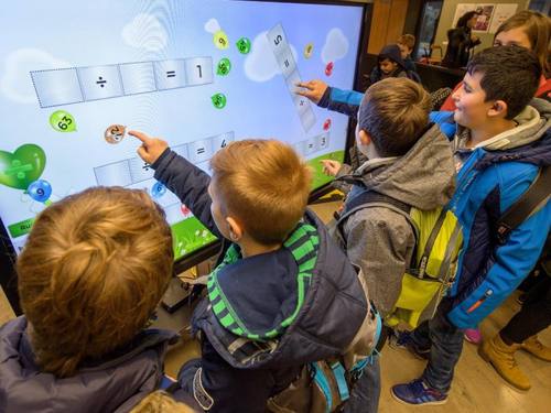 Schulkinder lösen beim 10. Nationalen IT-Gipfel in Saarbrücken auf einem großen Touchscreen Rechenaufgaben. Foto: Oliver Dietze