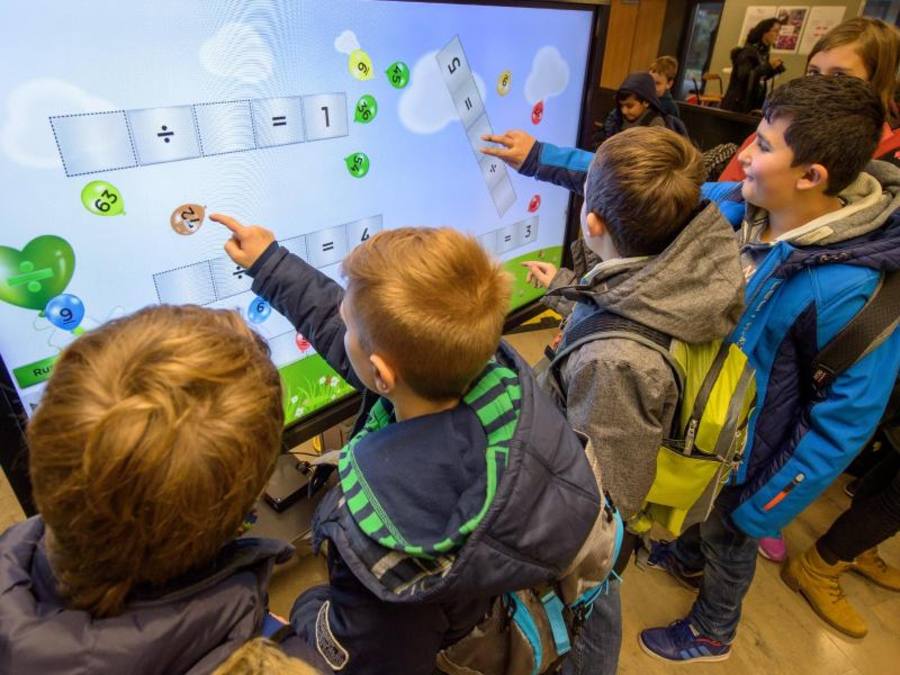 Schulkinder lösen beim 10. Nationalen IT-Gipfel in Saarbrücken auf einem großen Touchscreen Rechenaufgaben. Foto: Oliver Dietze