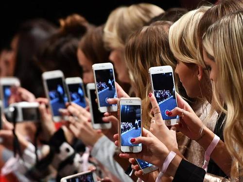 Frauen mit Smartphones filmen und fotografieren auf der Berlin Fashion Week. Foto: Jens Kalaene