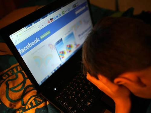Ein Junge reibt sich beim Betrachten der Facebook-Seite die Augen. Foto: Oliver Berg/Archiv