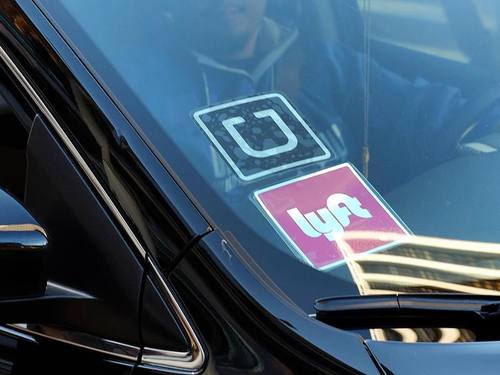 An der Scheibe eines Autos hängen Aufkleber der beiden Fahrdienst-Vermittler «Uber» und «Lyft». Foto: Richard Vogel/Archiv
