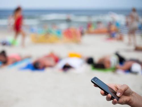 Mobiltelefon am Strand: Verbraucherschützer warnen bei der Abschaffung der Roaminggebühren vor versteckten Kostenfallen. Foto: Daniel Naupold