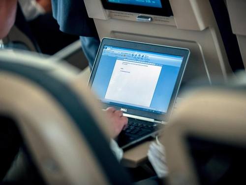 Ein Mann arbeitet in einem Flugzeug auf dem Weg nach Berlin an seinem Laptop. Foto: Michael Kappeler