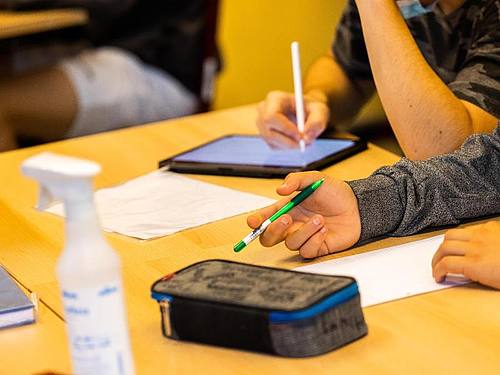 Ein Schüler hält beim Unterricht in seiner Klasse einen Stift, während ein anderer mit einem Tablet arbeitet. Foto: Philipp von Ditfurth/dpa